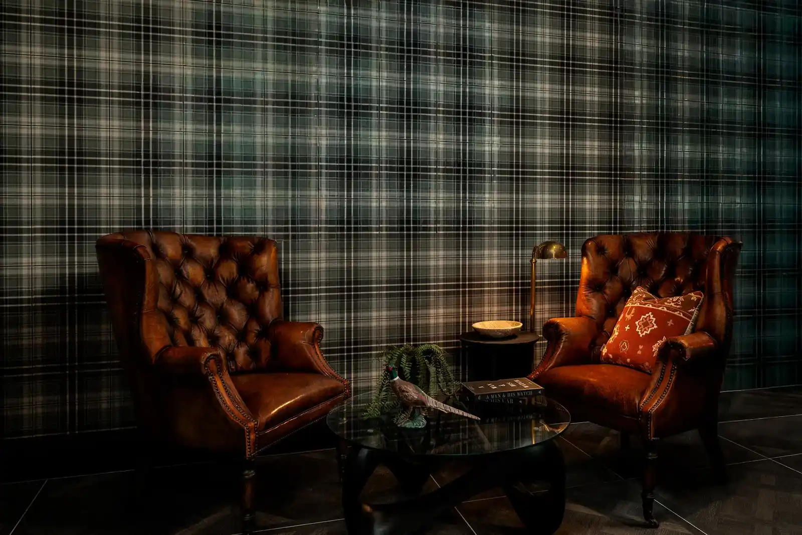 Moody and dramatic cigar lounge with two leather chairs positioned again a plaid wall with dramatic lighting